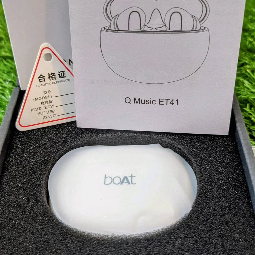 Boat Q Music ET41 wireless earbuds in a box with a certificate of qualification on a grass background