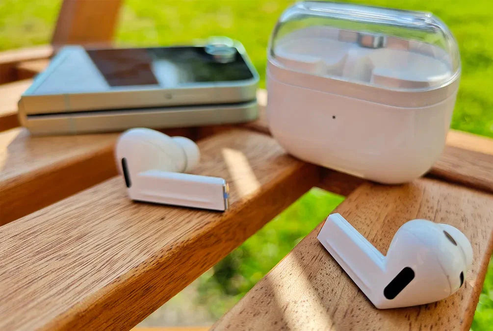 Wireless earbuds with charging case on a wooden surface outdoors
